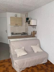 a white couch in a room with a kitchen at Studio Cosy pied des pistes in Saint-Léger-les-Mélèzes