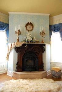 a living room with a fireplace with a clock on the wall at Alexander Mansion Bed and Breakfast in Winona