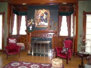 a living room with two red chairs and a fireplace at Alexander Mansion Bed and Breakfast in Winona