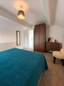 a bedroom with a blue bed and a wooden cabinet at New Top Floor Large 1- Bed Flat in Morecambe