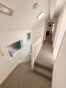 a staircase in a home with white walls and carpet at New Top Floor Large 1- Bed Flat in Morecambe