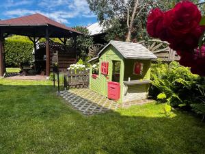 a green play house with a red door in the grass at Andromeda in Mikoszewo