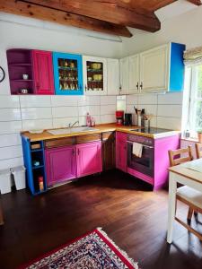 a kitchen with pink cabinets and a wooden floor at Ferienhaus am Schulsee in Mölln