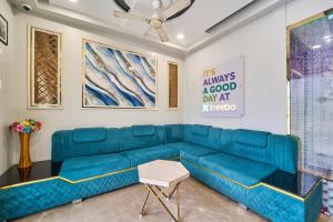 a living room with a blue couch and paintings at Treebo Park View Villa in Jodhpur