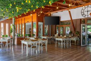 a restaurant with tables and chairs and a flat screen tv at Holiday Hotel Siófok in Siófok
