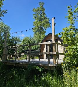 a wooden gazebo with a bench on a bridge at Tiny House De Kwekfink in Westergeest