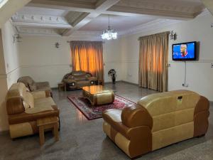 a living room with leather furniture and a flat screen tv at Christabel Hotel and Apartment Rayfield Jos in Jos