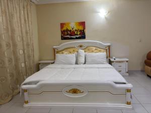 a bedroom with a white bed with a white bedspread at Christabel Hotel and Apartment Rayfield Jos in Jos
