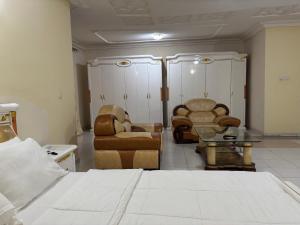 a room with a bed and chairs and a table at Christabel Hotel and Apartment Rayfield Jos in Jos
