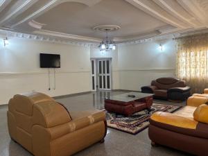 a living room with leather furniture and a flat screen tv at Christabel Hotel and Apartment Rayfield Jos in Jos