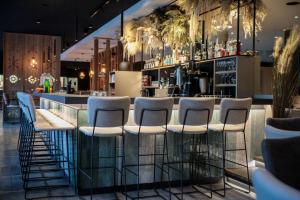 a bar with white stools in a restaurant at Revier Boutique Hotel Kaprun in Kaprun +41 photos