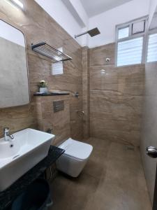 a bathroom with a white sink and a toilet at EMBASSY PARK - Near US consulate, Apollo hospital, Sankaranethralaya in Chennai +17 photos