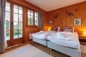 two beds in a room with wooden walls and windows at Chalet Belle Poncke by Jolidi in Nendaz