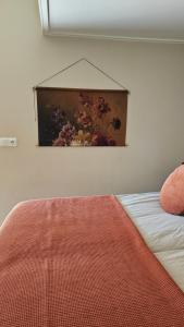 a bedroom with a painting on the wall next to a bed at Tiny House De Klyster in Westergeest