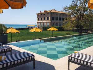 a swimming pool with two umbrellas and a building at La Posta Vecchia Hotel in Ladispoli