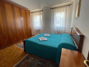 a bedroom with a green bed with two towels on it at Casa Cadore Grea in Grea