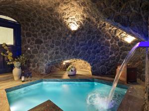 a pool in a room with a stone wall at Secret Gem Suites in Oia