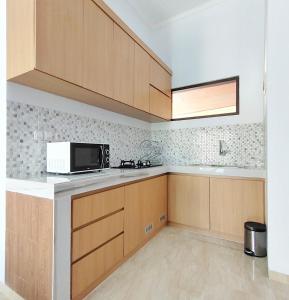 a kitchen with wooden cabinets and a microwave at Canggu Rice Field Villa 8B in Dalung