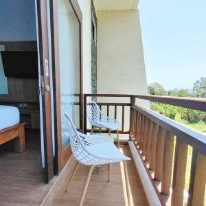 a balcony with two chairs and a bed at Canggu Rice Field Villa 8B in Dalung