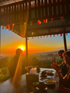 a group of people sitting around a table with the sunset at Haris Homestay & Cottages in Senaru