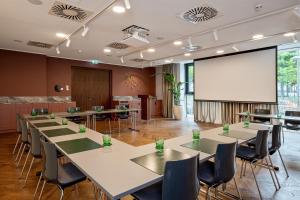 a conference room with tables and a projection screen at MAXX by Steigenberger Vienna in Vienna