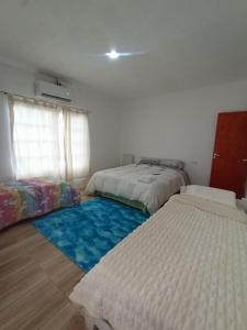 a bedroom with two beds and a blue rug at Hotel Maipú in Maipú