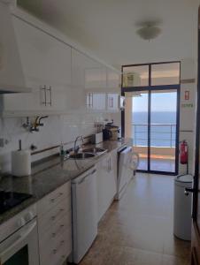 a large white kitchen with a view of the ocean at Edifício Panorâmico - Falésia de Sesimbra in Sesimbra