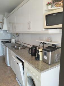 a white kitchen with a sink and a microwave at Edifício Panorâmico - Falésia de Sesimbra in Sesimbra +26 photos