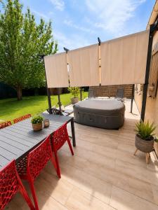 a patio with a bed and a wooden table and benches at Maison de charme avec Jacuzzi privé in Sarcelles
