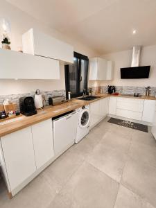a kitchen with white cabinets and a washing machine at Maison de charme avec Jacuzzi privé in Sarcelles