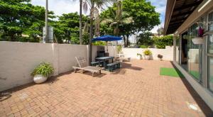 a patio with a table and chairs and an umbrella at 1 Seabreeze Cottage in Durban