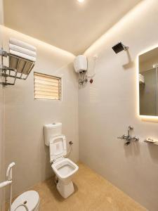 a white bathroom with a toilet and a mirror at Hotel Pushparaj Puri - Beach front Hotel near Light House - Sea Facing AC Rooms - with Restaurant, Parking Facilities in Puri