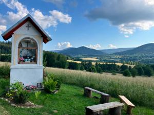 a small chapel in a field with mountains in the background at Anmar Pokoje Narty Rowery in Stronie Śląskie