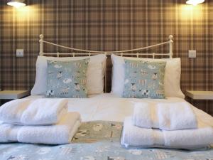 a bed with white blankets and pillows on it at 12A Elm Court in Keswick +2 photos