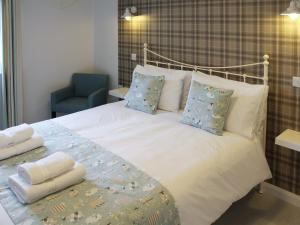 a bedroom with a white bed with pillows and a chair at 12A Elm Court in Keswick