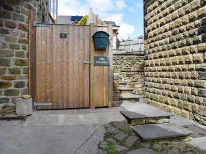 a wooden gate with a sign on it next to a brick wall at Little Plumtree in Addingham