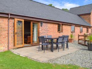 a patio with a table and chairs in front of a building at Talog Barn-Uk31366 in Tregynon