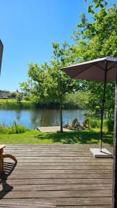 a wooden deck with an umbrella next to a river at Tiny house De Ljip in Westergeest