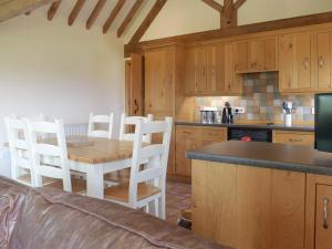 a kitchen with a wooden table and white chairs at Talog Barn-Uk31366 in Tregynon +6 photos