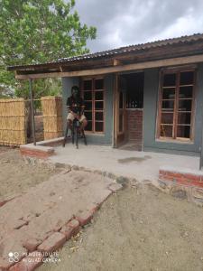 a man sitting in a chair in front of a house at Mabuu Drive Inn in Waya