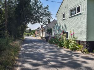 a street in a small town with a house and flowers at The Green One On The End in Thurton