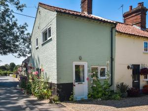 a green and white house with flowers in front of it at The Green One On The End in Thurton