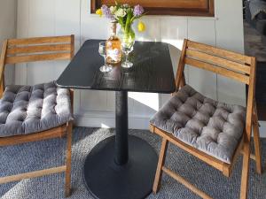a black table with two chairs and a vase of flowers at Willow's Rest in Crafthole