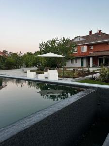 a pool with a table and an umbrella next to a house at Rouge Cottage nel Roero in Sanfrè