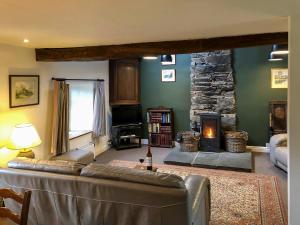 a living room with a couch and a stone fireplace at Little Knott in High Nibthwaite
