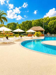 a resort swimming pool with umbrellas and chairs at Tika Bungalow - Pisicne, Wifi, Grande Terrasse privée et Accès Plage à pied in Grand-Bourg