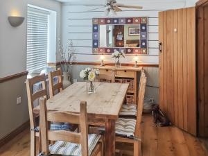 a dining room with a wooden table and a mirror at Moorhens Cottage in Somerford Keynes