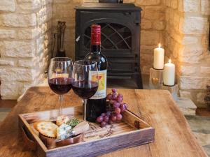 a bottle of wine and two glasses on a table at Moorhens Cottage in Somerford Keynes