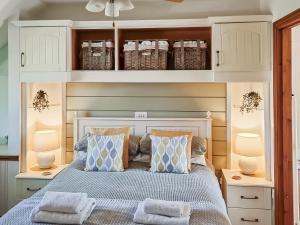 a bedroom with a bed with pillows and two lamps at Moorhens Cottage in Somerford Keynes