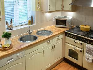 a kitchen with a sink and a stove top oven at Moorhens Cottage in Somerford Keynes +13 photos